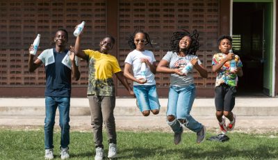 Five school children in Barbados in a line, facing the camera and jumping in the air.