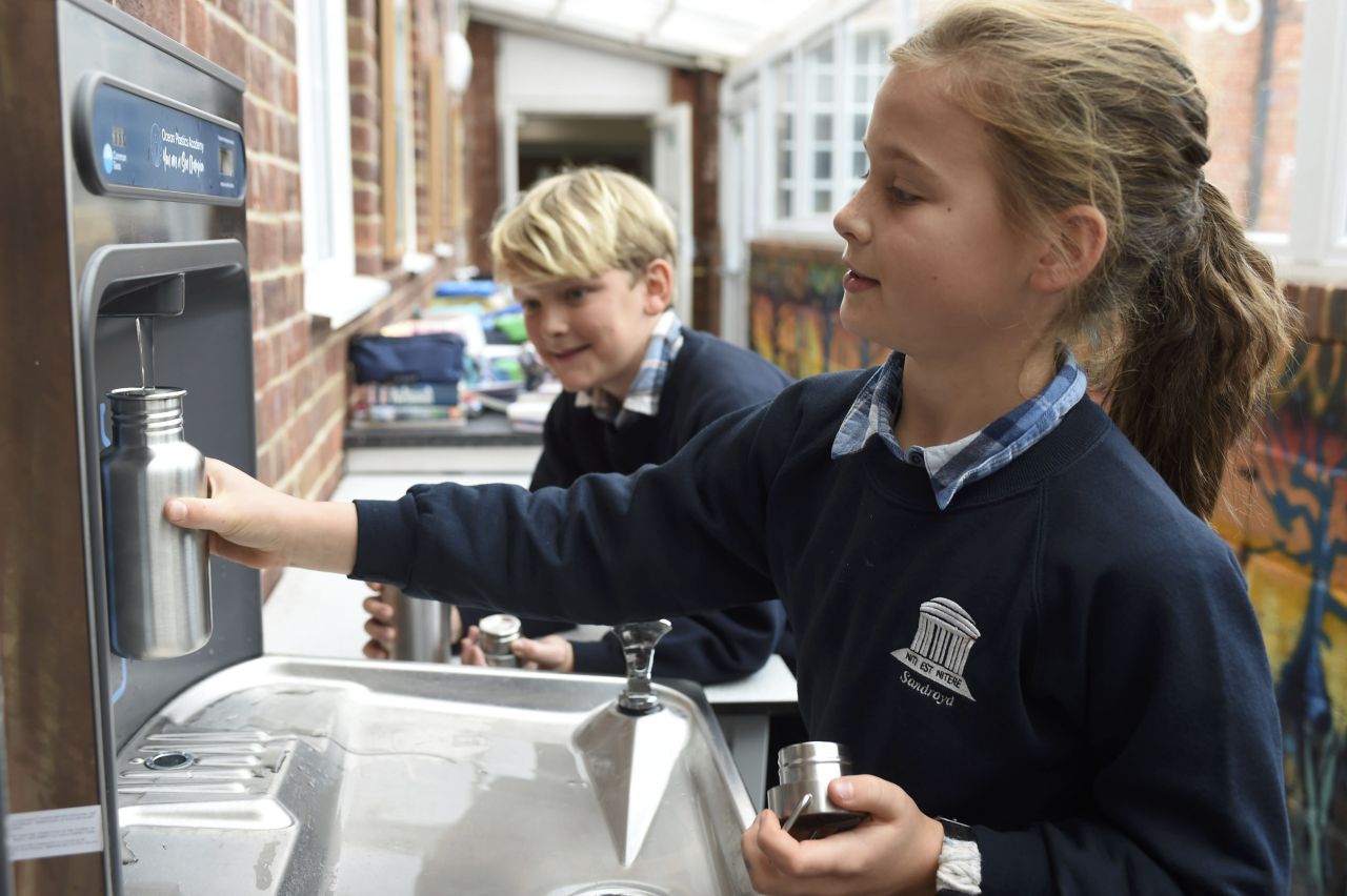 Two children filling reusable water bottles