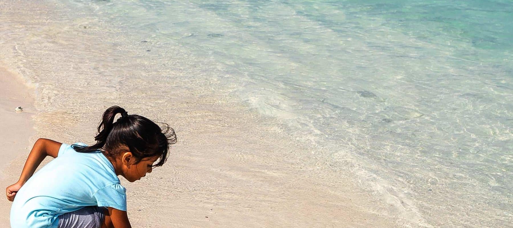 A young girl plays in the shorline of a tropical beach in The Maldives.