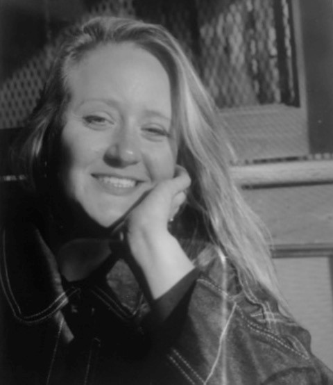 Profile photo of Nicole Dagenais, Designer at Common Seas. Nicole wears a dark knitted jumper. She leans her chin on her hand and smiles at the camera. Photo is in gresyscale.