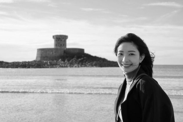 Profile photo of Jiawei Liu, School Engagement Officer at Common Seas. Jiawei is wearing a light-coloured turtle neck and a dark jacket, and smiling at the camera side-on. Photo is in greyscale.