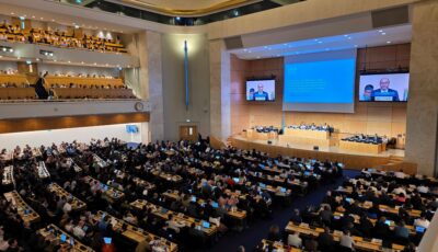 INC5.2 Global Plastics Treaty closing plenary session. The Assembly Hall in the UN's Palais des Nations shot from a high angle, with delegates seated and a screen showing the session.