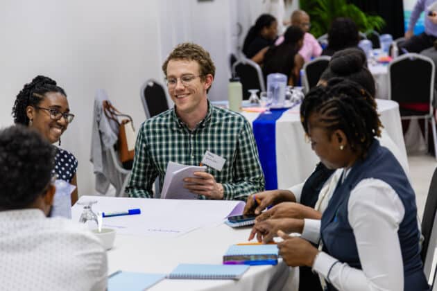 Workshop participants around a table smiling and discussing.
